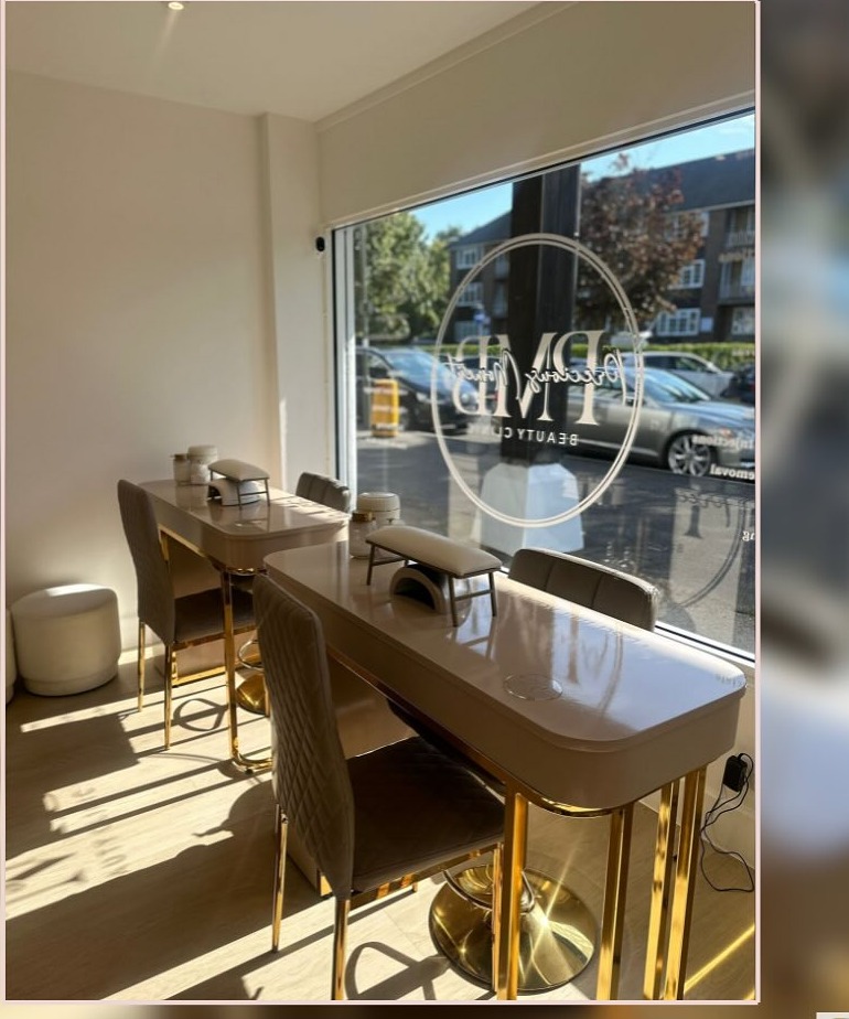 Nail stations in the window of Precious Moments Beauty Clinic, Banstead, with gold-framed desks and etched PMB logo