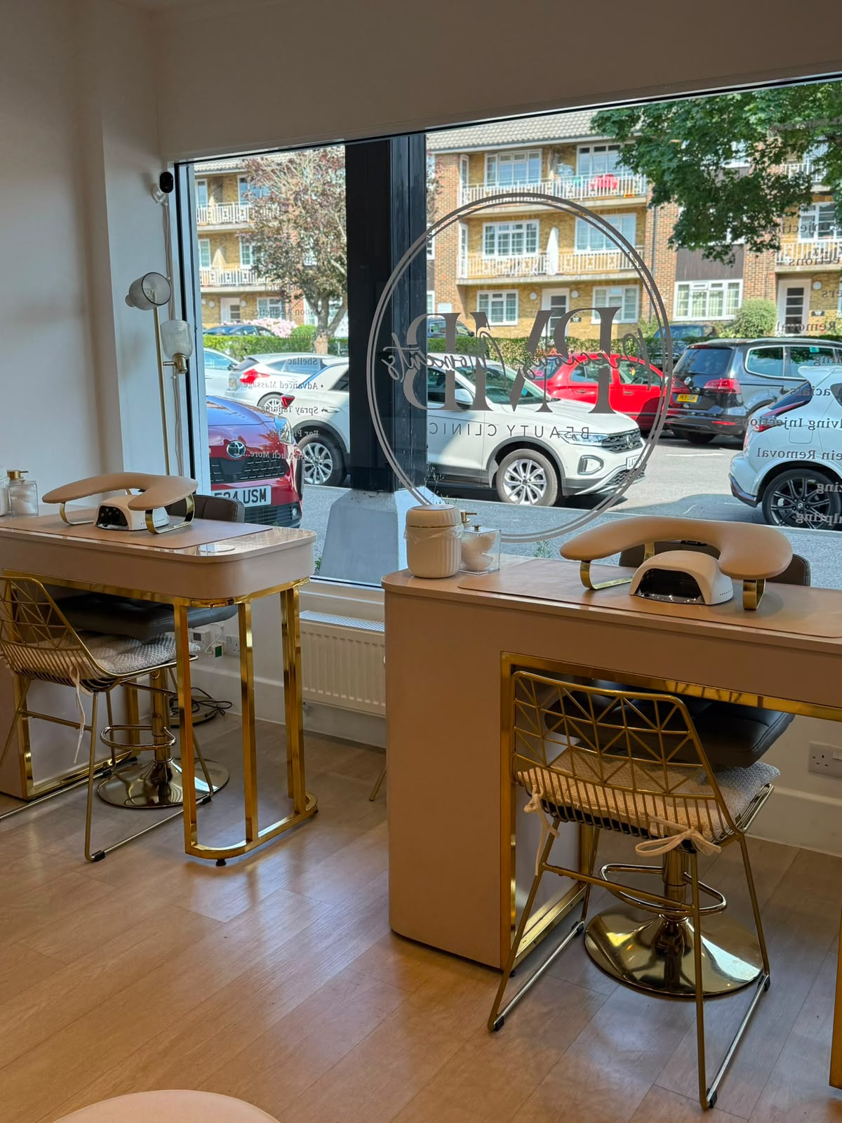 Manicure stations with gold chairs and pink desks by the window at Precious Moments Beauty Clinic, Banstead